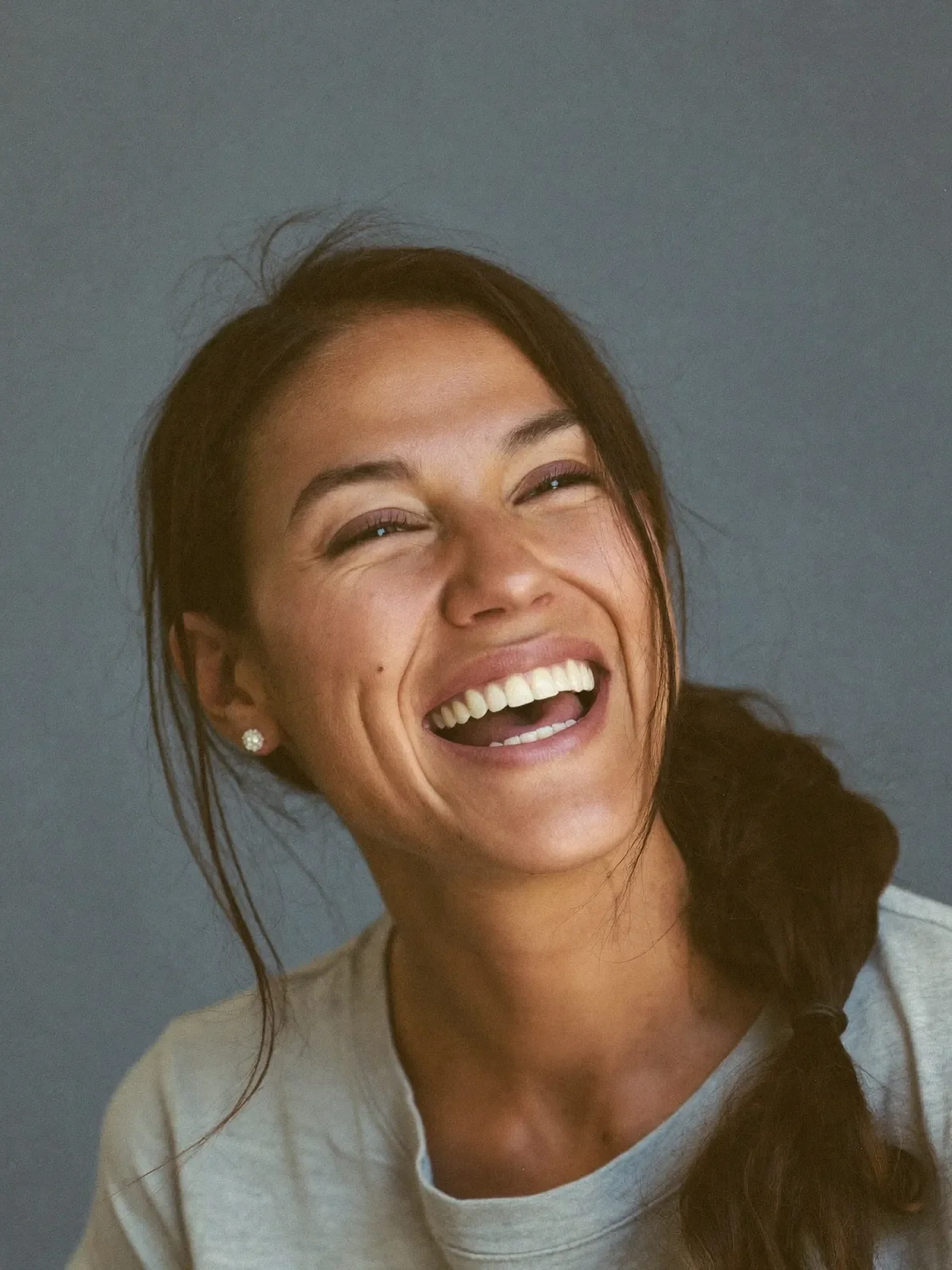 Woman laughing, photographed against a plain backdrop