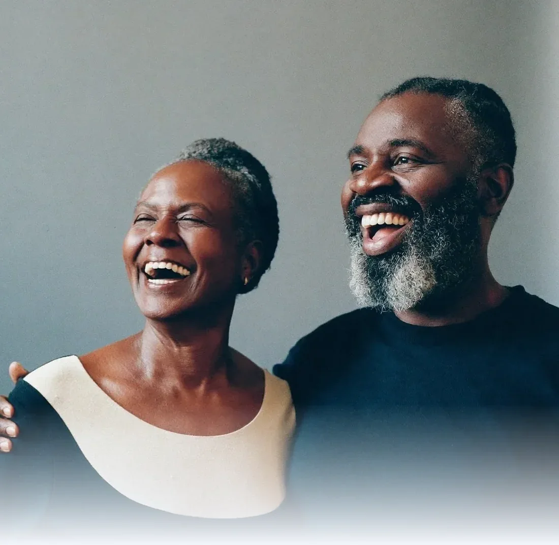 Couple laughing together against a plain studio backdrop