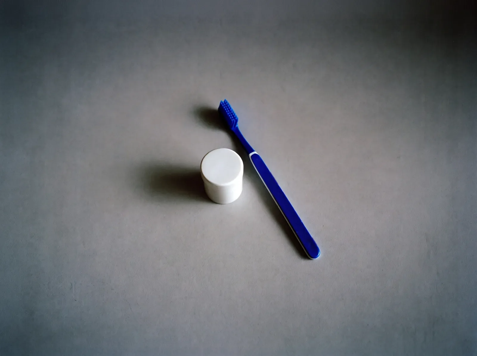 Blue toothbrush and floss on a plain backdrop